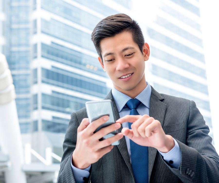 Man using his mobile phone while outside looking pleased with it