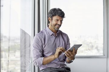 Man examining a tablet and smiling at what he is reviewing.