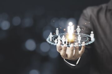 A person's hand holding a glowing circle of human figures.symbolizing leadership, teamwork, or community.