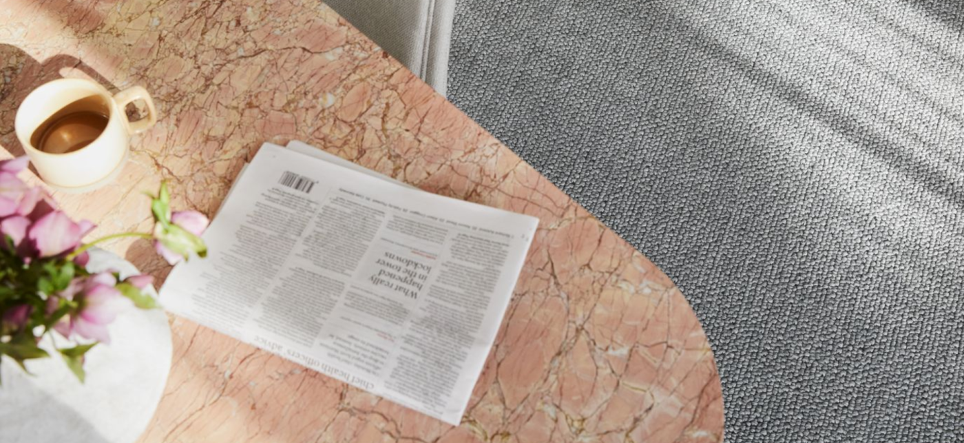 Close up of coffee and a newspaper sitting on a marble desktop