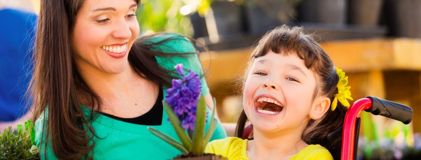 Carer with a happy, laughing girl in a wheelchair.