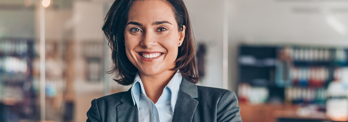 Confident businesswoman in a grey blazer smiling in a modern office environment