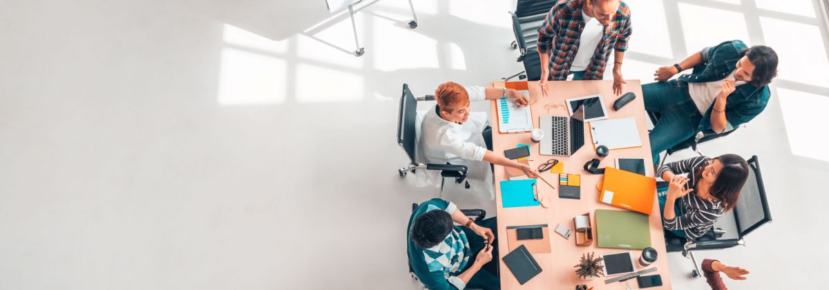 Informal meeting in spacious room with laptops and colourful office stationery.